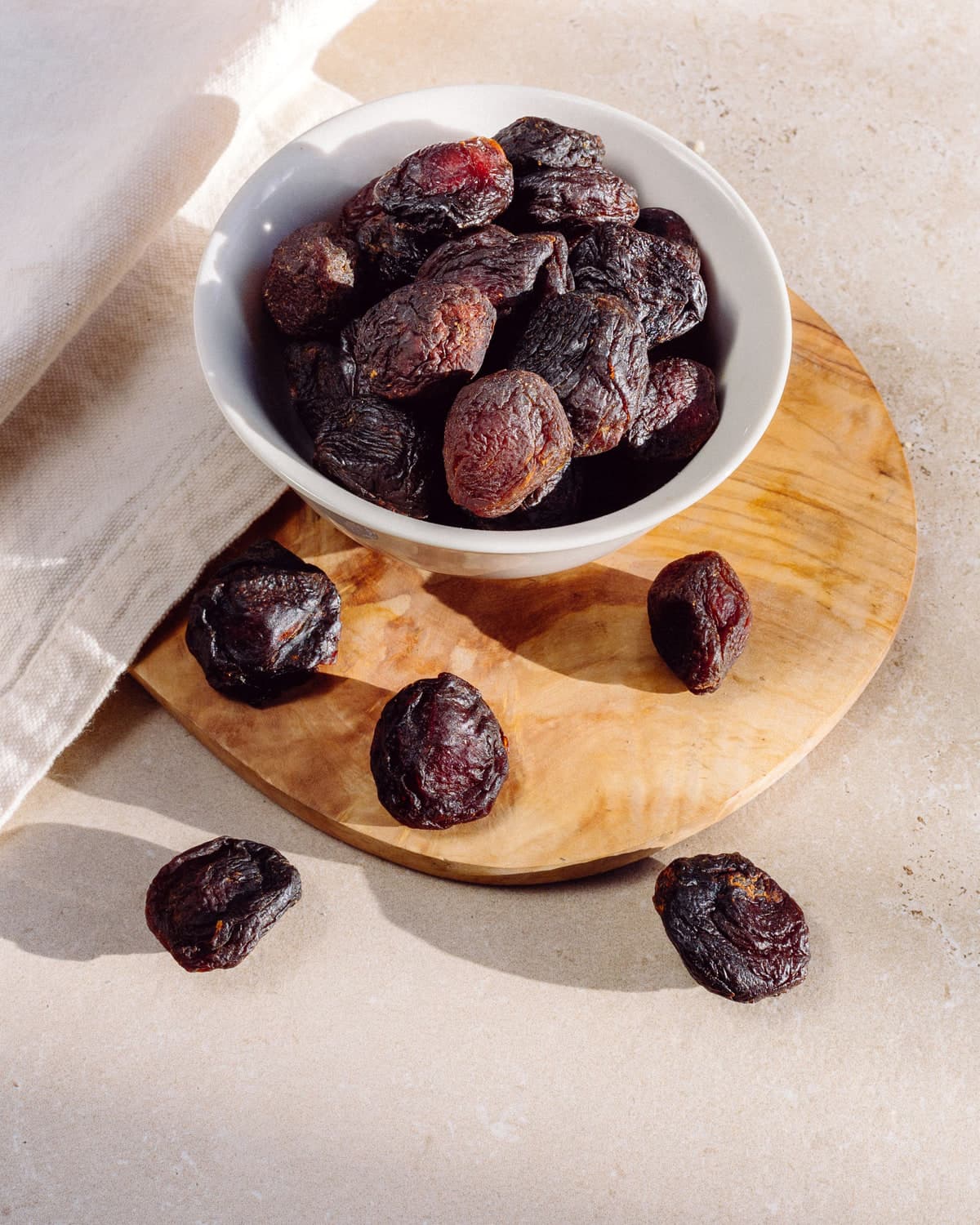 BM dried plums in a white bowl on a wooden board