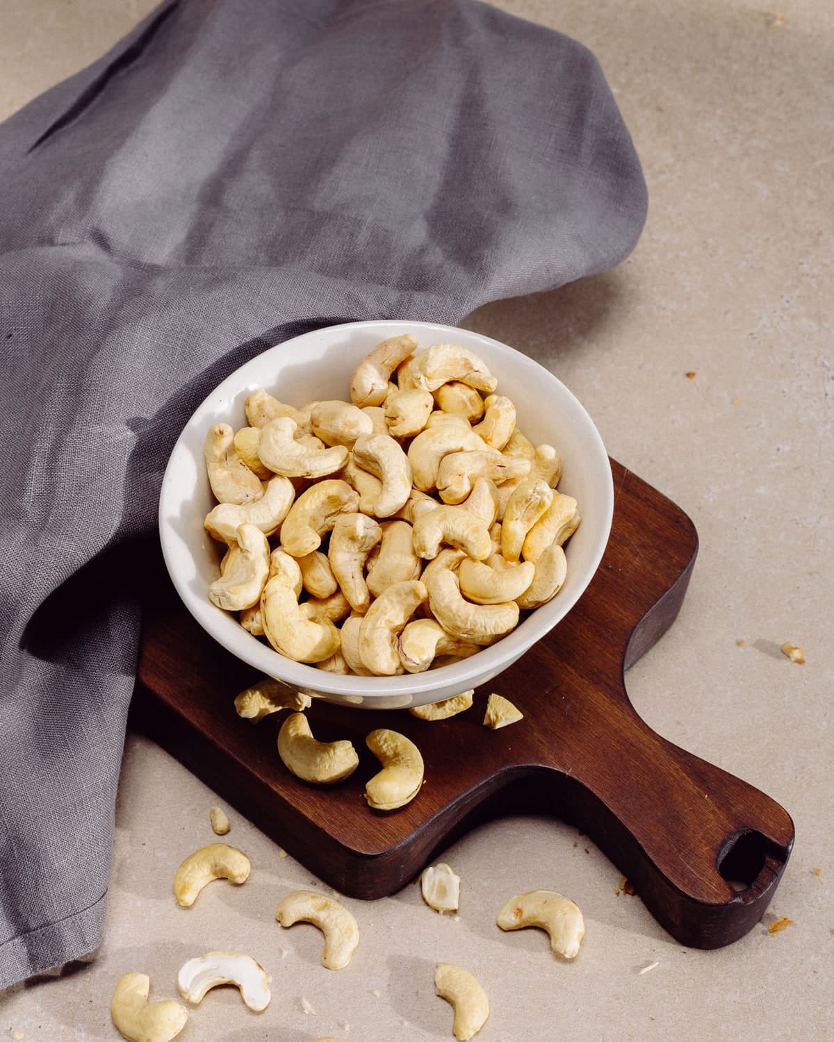 BM plain cashews in a white bowl on a wooden board