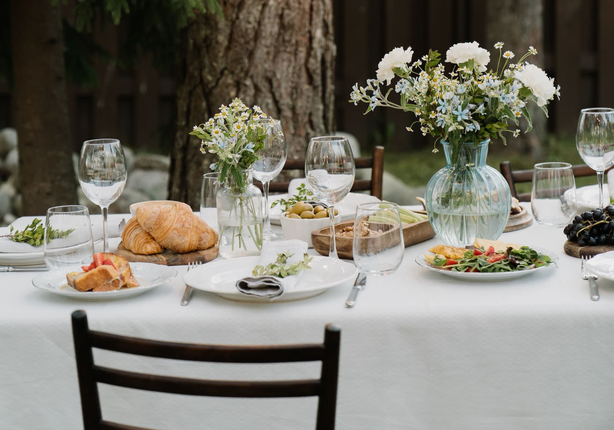 An outdoor table laid with flowers under string lights